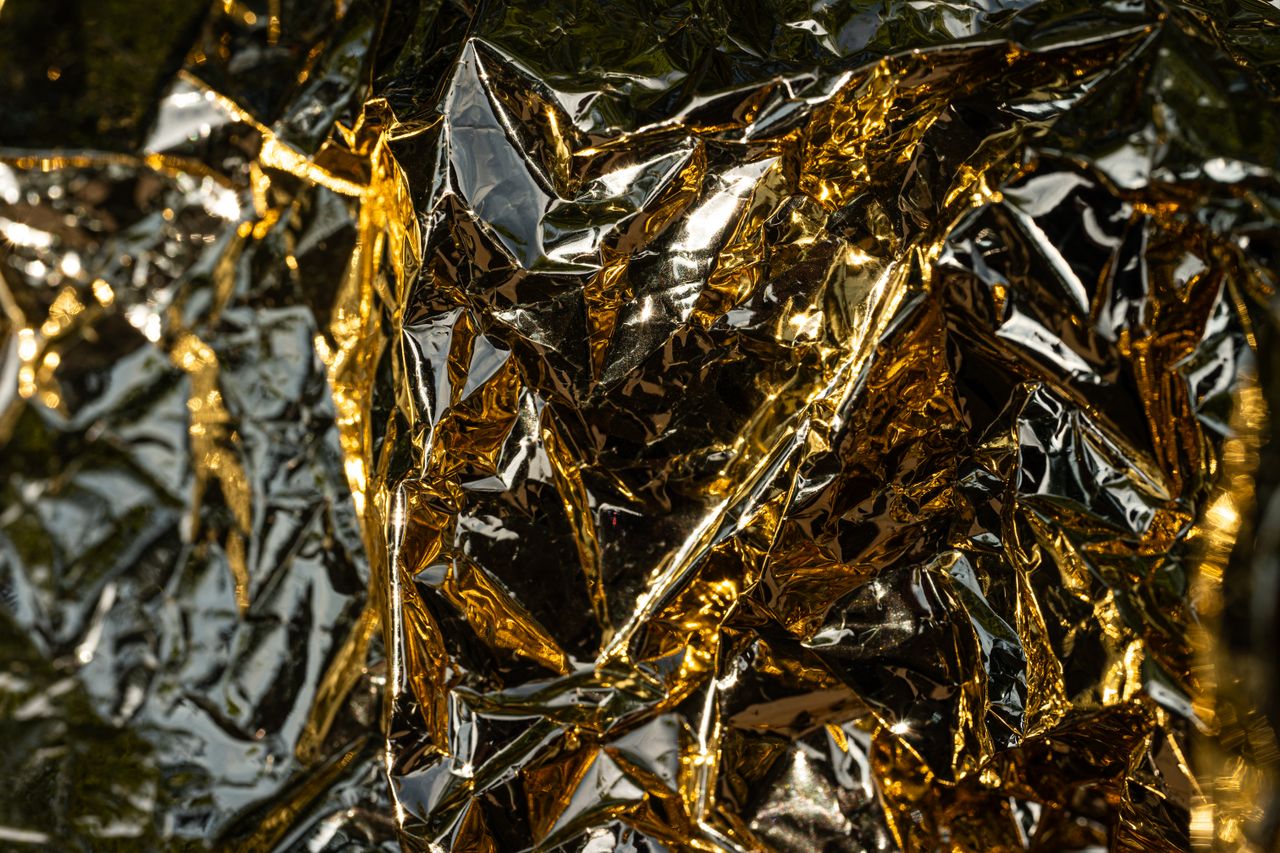A close-up, detailed view of crumpled gold foil with intricate reflections and textures.